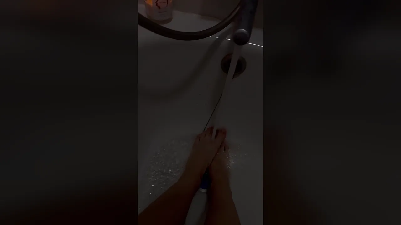 Beautiful young woman worships her feet in the bathroom